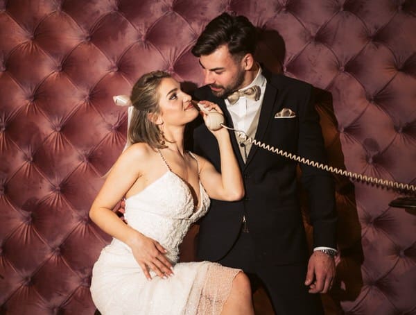 wedding couple is looking at each other while the bride is using the oldtime phone