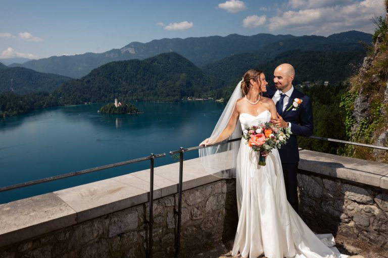 Scenic view on the Lake Bled from the castle by groom and bride being hugging each other on their wedding day
